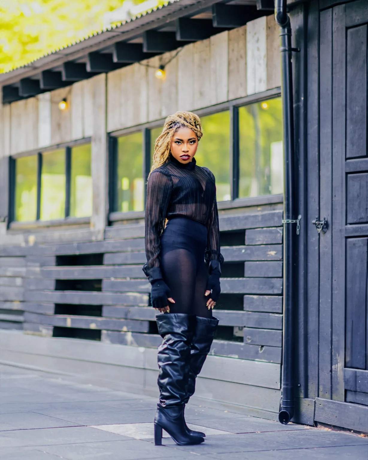 Ret Qut in a full black outfit and tall boots